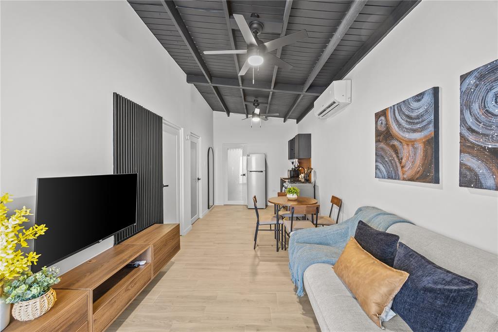 A living room features a dark wood-paneled ceiling, a sofa, a television, and a kitchenette — 8 BORIQUEN, SABANA GRANDE, PR