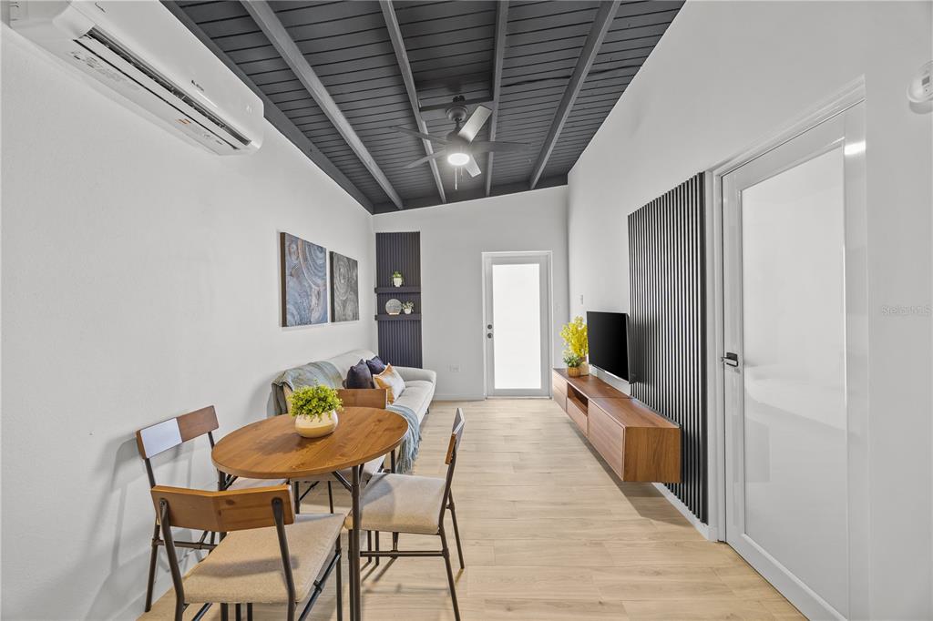 A modern living and dining area features a wood-slat accent wall, vaulted ceiling, and furniture — 8 BORIQUEN, SABANA GRANDE, PR