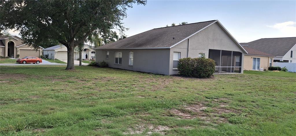 A side view of a single-story house with a screened-in lanai and grassy yard — 3737 ROLLINGSFORD CIRCLE, LAKELAND, FL