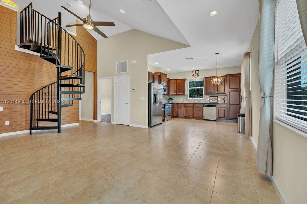A living area with a spiral staircase and tile flooring opens to a wooden kitchen — 4357 Cascada Cir # 4357, Cooper City FL 33024, COOPER CITY, FL