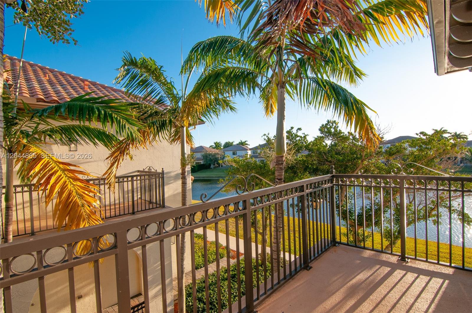 A balcony with a metal railing overlooks a lake and palm trees under a clear sky — 4357 Cascada Cir # 4357, Cooper City FL 33024, COOPER CITY, FL