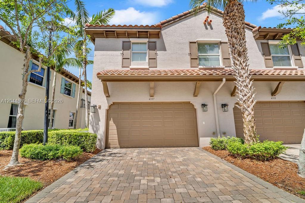 A two-story townhouse exterior with a tan stucco facade, brown garage door, and paver driveway — 4357 Cascada Cir # 4357, Cooper City FL 33024, COOPER CITY, FL