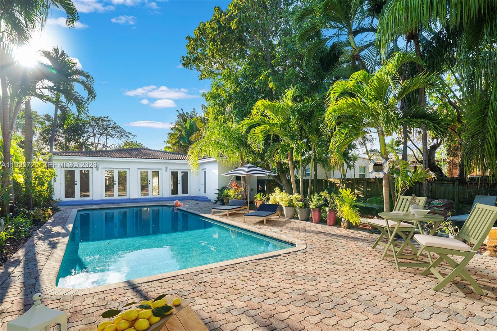 A backyard features a swimming pool, brick patio, lounge chairs, and tropical landscaping — 3755 Royal Palm Ave, Miami Beach FL 33140, MIAMI BEACH, FL