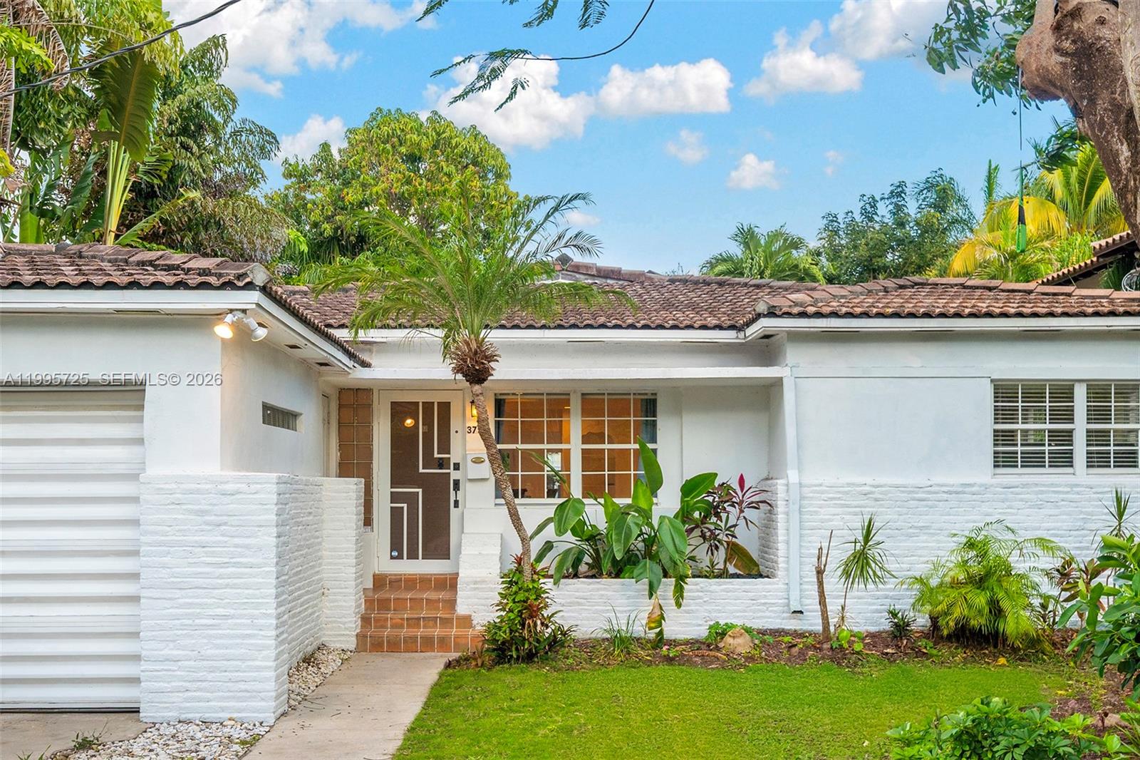 The exterior of a white house features a tiled roof, a small palm tree, and landscaping — 3755 Royal Palm Ave, Miami Beach FL 33140, MIAMI BEACH, FL