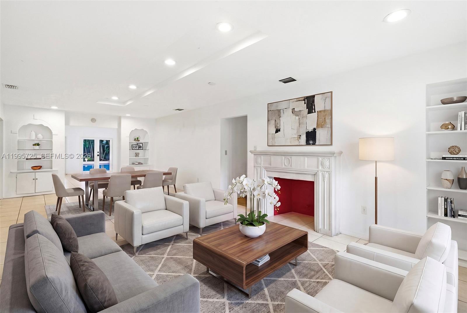 A living room with a fireplace, white armchairs, a gray sofa, and a dining area — 3755 Royal Palm Ave, Miami Beach FL 33140, MIAMI BEACH, FL