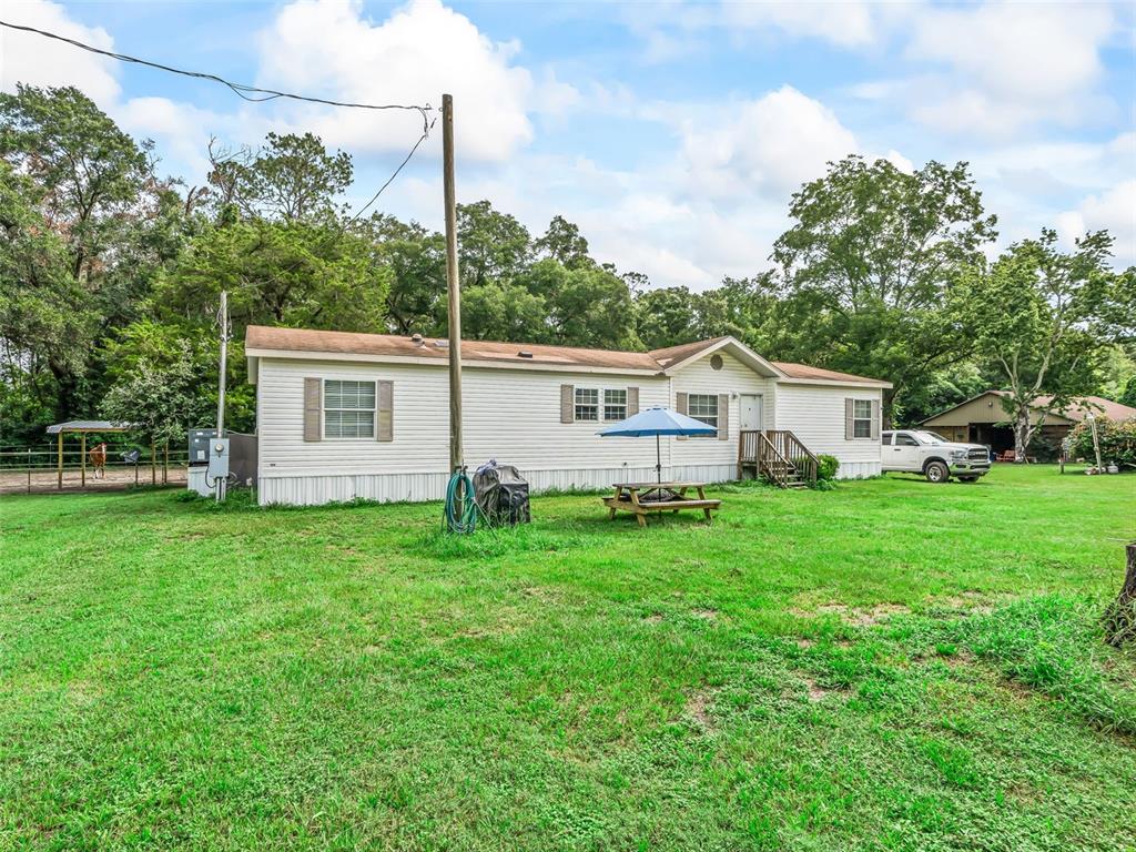 A single-story manufactured home with white siding sits on a large grassy lot — 4603 NW 61ST LANE, OCALA, FL