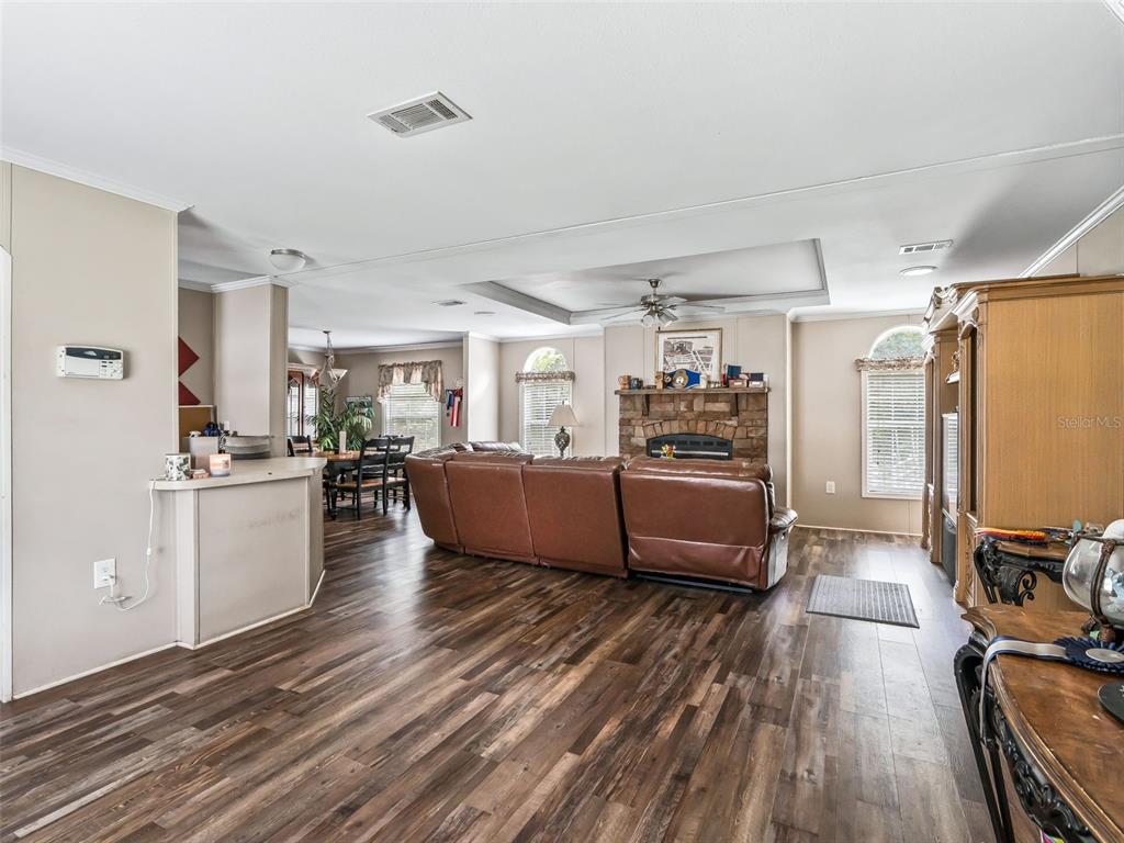 A living room with wood-look flooring, a stone fireplace, and a large brown leather sofa — 4603 NW 61ST LANE, OCALA, FL