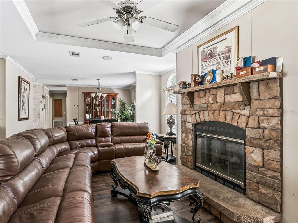 A living room features a stone fireplace, a large brown leather sectional, and wood flooring — 4603 NW 61ST LANE, OCALA, FL