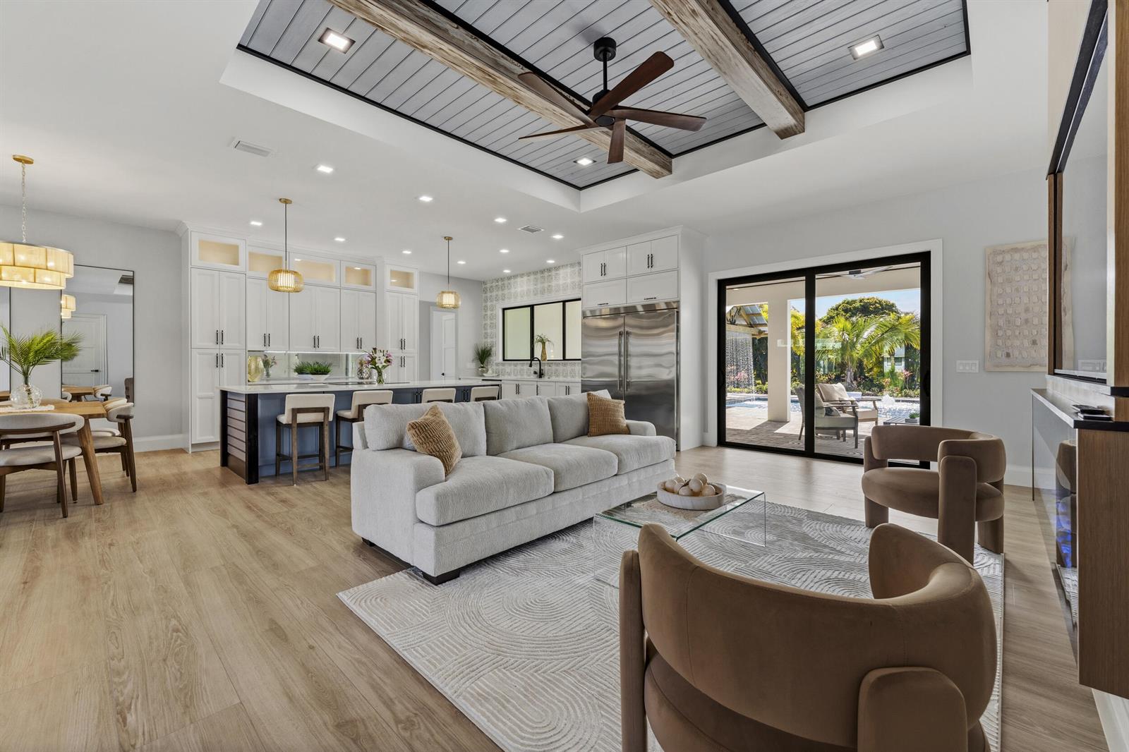 An open-concept living room and kitchen featuring a coffered ceiling, wood beams, and sliding doors — 16149 73rd Terrace N, West Palm Beach FL 33418, WEST PALM BEACH, FL