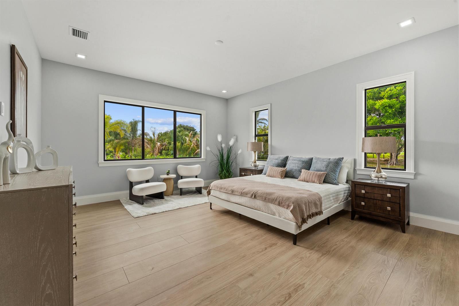 A bedroom features light wood flooring, a bed with blue pillows, and two accent chairs — 16149 73rd Terrace N, West Palm Beach FL 33418, WEST PALM BEACH, FL