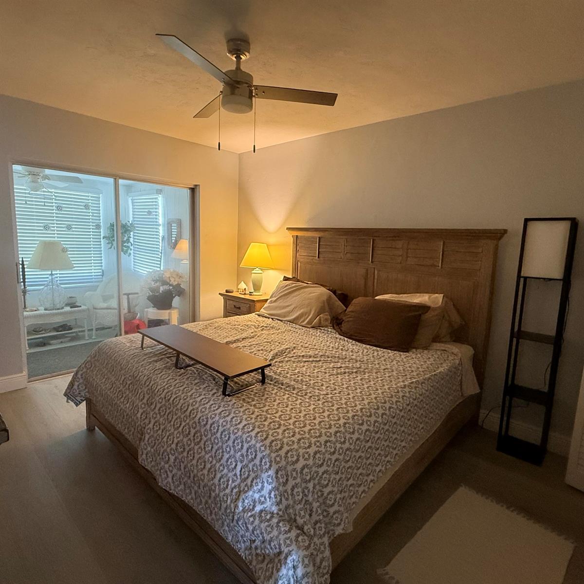 A bedroom features a wooden bed frame, a ceiling fan, and a sliding glass door — 2102 Lake Osborne Drive # 20, FL 33461, FL