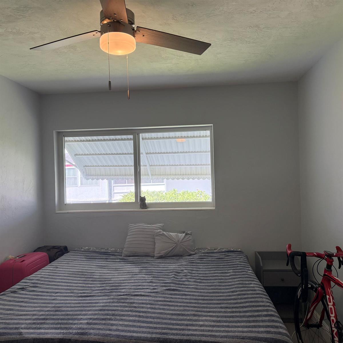 A bedroom features a ceiling fan, a window with an awning, and a bed — 2102 Lake Osborne Drive # 20, FL 33461, FL