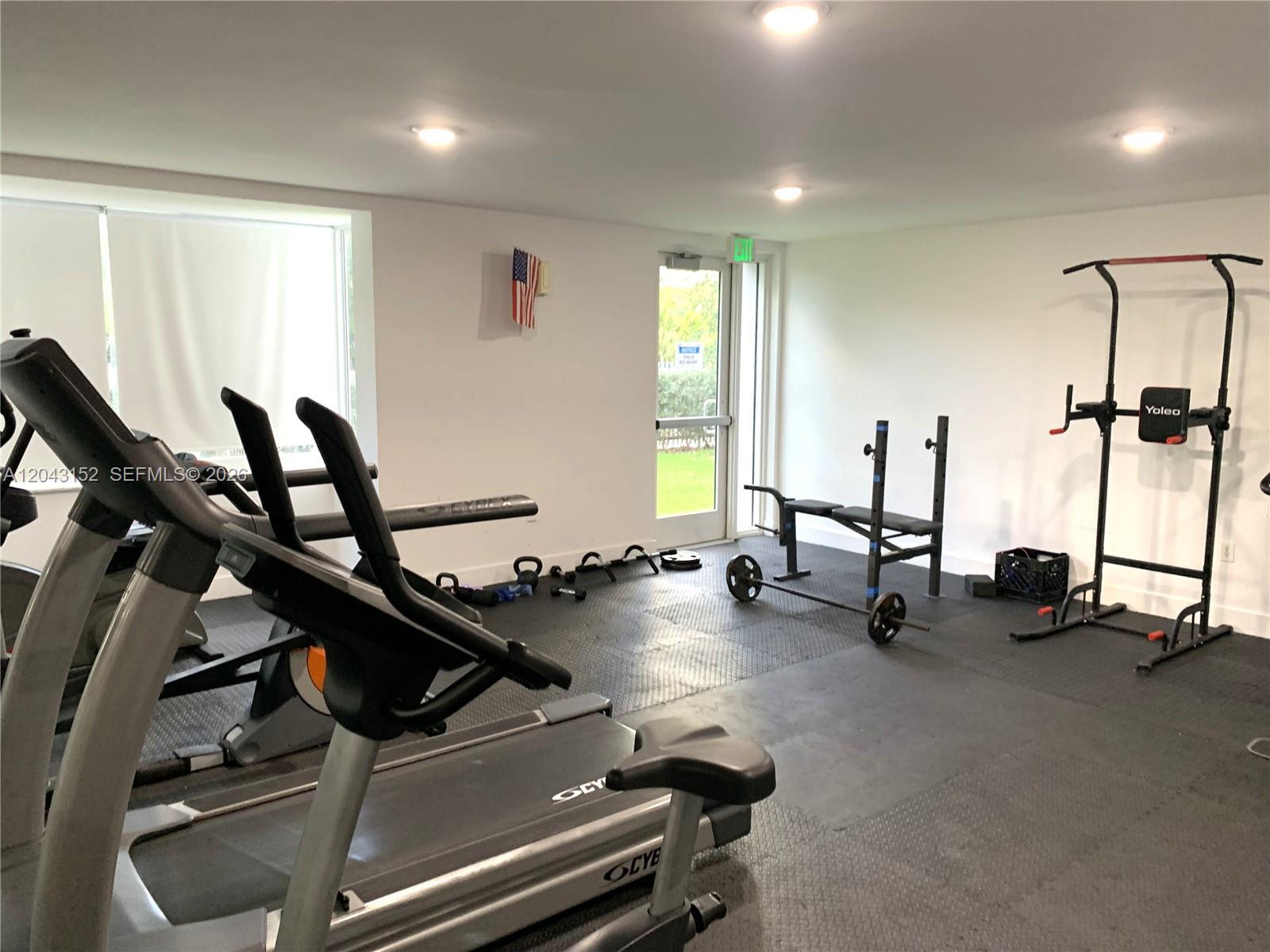 A home gym features rubber flooring, a treadmill, a weight bench, and a pull-up station — SUNNY ISLES BEACH, FL