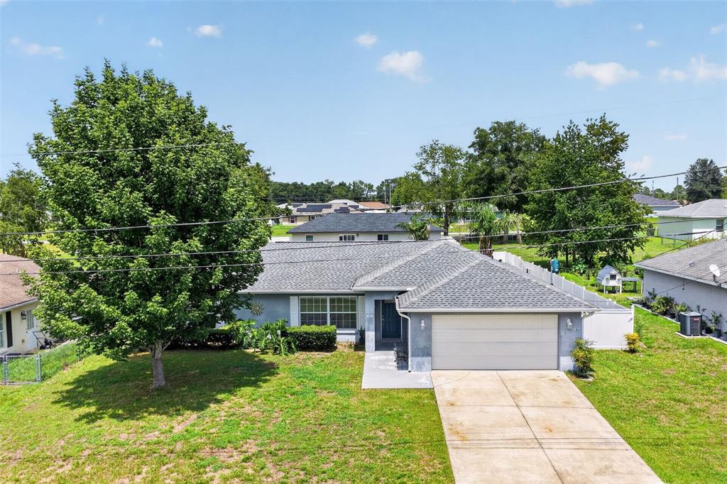 An aerial view shows a single-story house with a gray roof and a concrete driveway — 135 JUNIPER LOOP, OCALA, FL