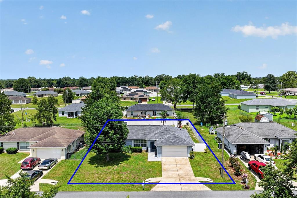 An aerial view shows a single-story house with a gray roof and a concrete driveway — 135 JUNIPER LOOP, OCALA, FL