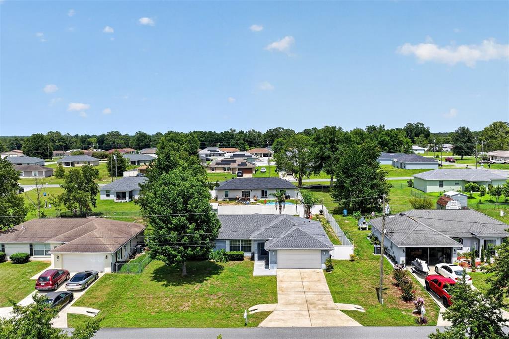 An aerial view shows a suburban neighborhood with single-family homes, driveways, and green lawns — 135 JUNIPER LOOP, OCALA, FL