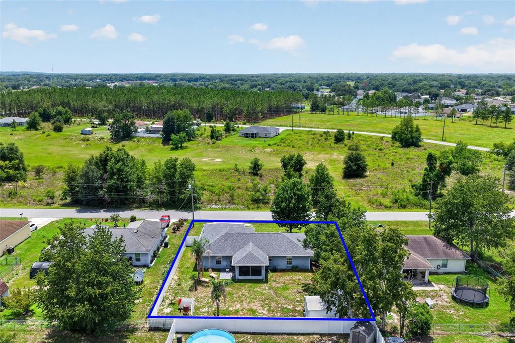 An aerial view shows a single-story house with a fenced backyard and a swimming pool — 135 JUNIPER LOOP, OCALA, FL