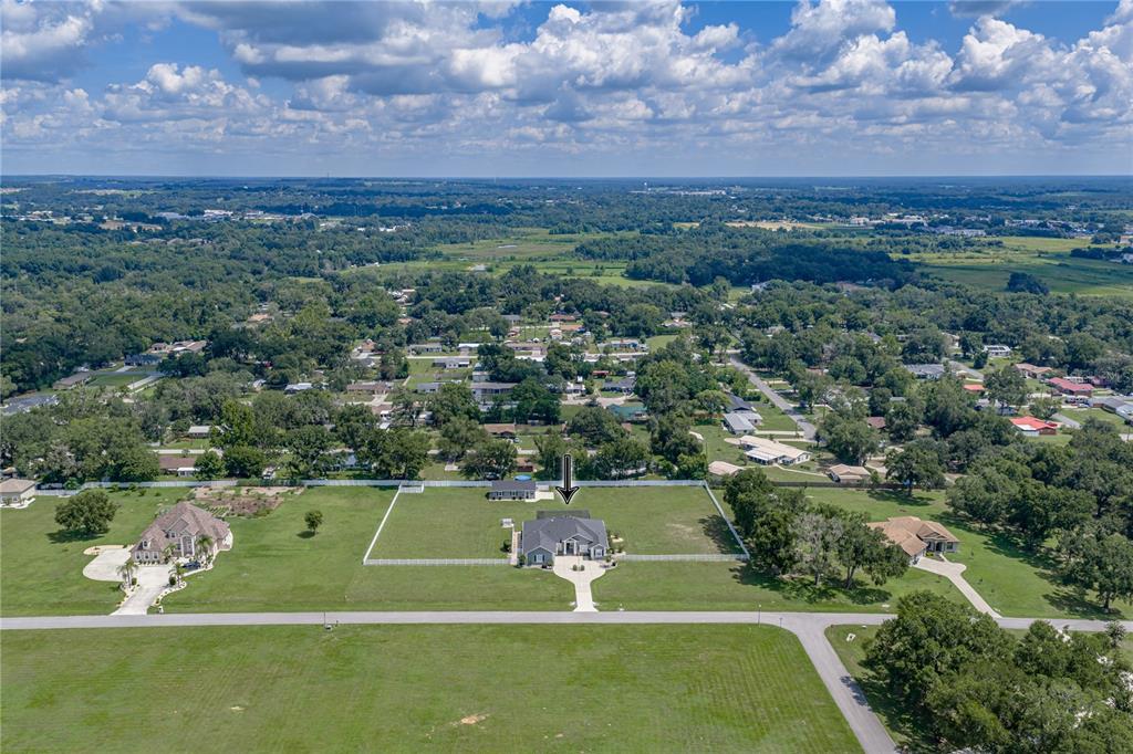An aerial view shows a single-story house with a fenced backyard in a rural neighborhood — 37405 HIGHRIDGE DRIVE, DADE CITY, FL