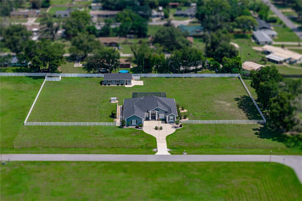 An aerial view shows a house with a pool enclosure and a detached garage — 37405 HIGHRIDGE DRIVE, DADE CITY, FL