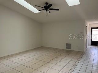 A spacious room with white walls, tiled flooring, a ceiling fan, and two skylights — 59 WELLWOOD LANE UNIT A & B, PALM COAST, FL