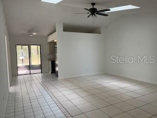 An open-concept living area features light-colored tile flooring, vaulted ceilings, and a sliding glass door — 59 WELLWOOD LANE UNIT A & B, PALM COAST, FL