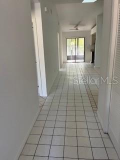 A hallway with white tile flooring leads toward a glass sliding door at the end — 59 WELLWOOD LANE UNIT A & B, PALM COAST, FL