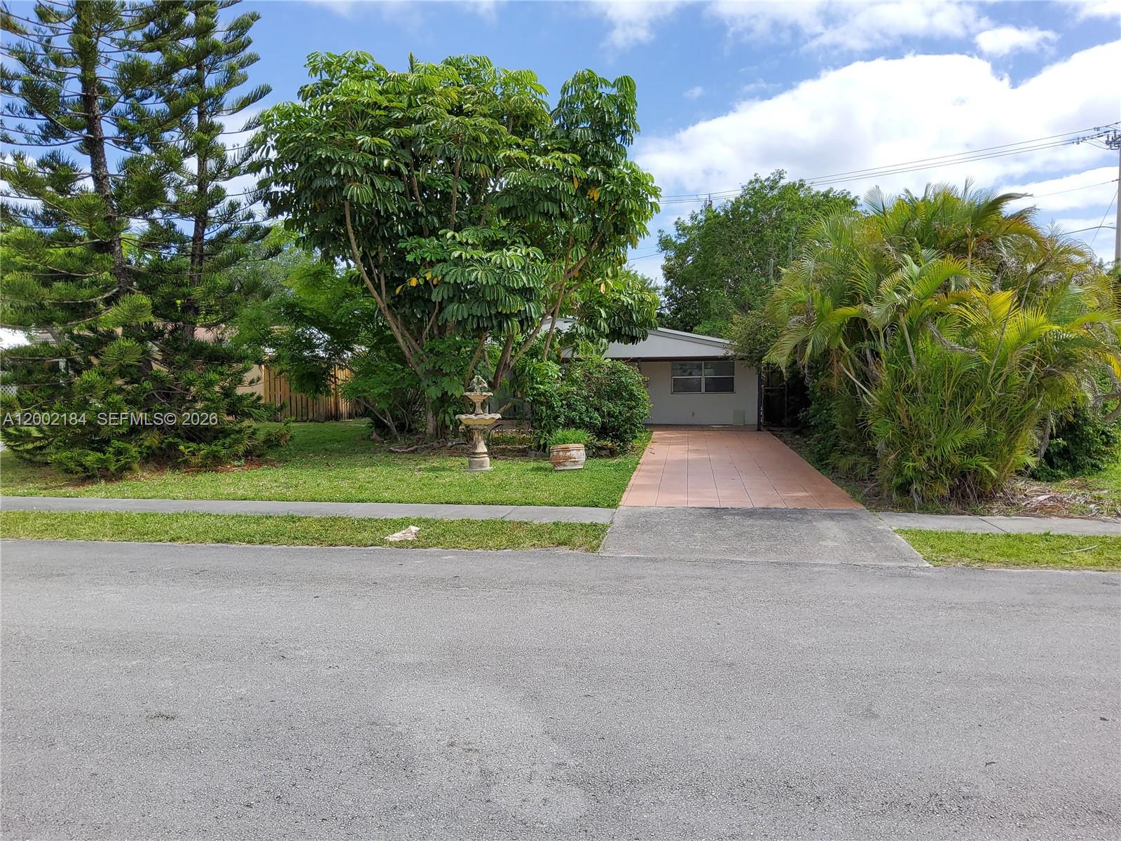 A single-story house features a tiled driveway, a front lawn, and mature landscaping — 1348 NE 176th St, North Miami Beach FL 33162, NORTH MIAMI BEACH, FL