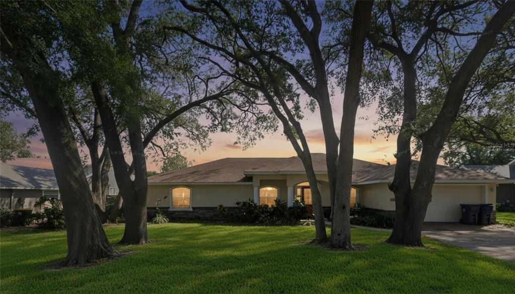 A single-story house with a lawn and large trees under a sunset sky — 2120 WILDWOOD LANE, AUBURNDALE, FL