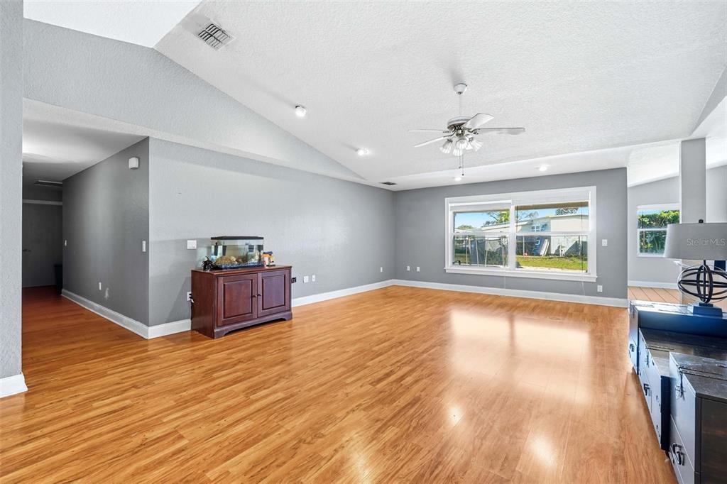 A spacious living room features light gray walls, wood-look flooring, and a vaulted ceiling — 2120 WILDWOOD LANE, AUBURNDALE, FL