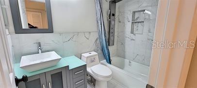 A bathroom features a vessel sink, a gray vanity, a toilet, and a tiled shower-tub — 911 WASHINGTON AVENUE SW UNIT 118, LARGO, FL