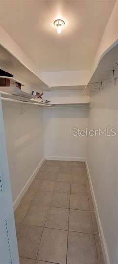 A walk-in closet with white shelving, tiled flooring, and a single ceiling light fixture — 911 WASHINGTON AVENUE SW UNIT 118, LARGO, FL