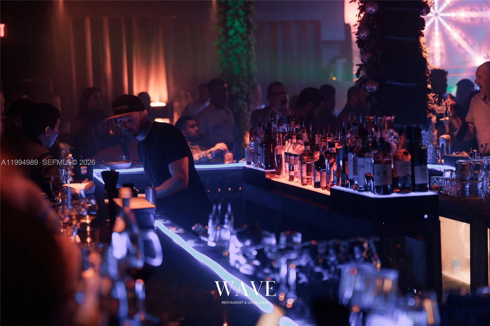 A dimly lit bar area features a bartender serving customers at a glowing counter — 115 S 20th Ave, Hollywood FL 33020, HOLLYWOOD, FL