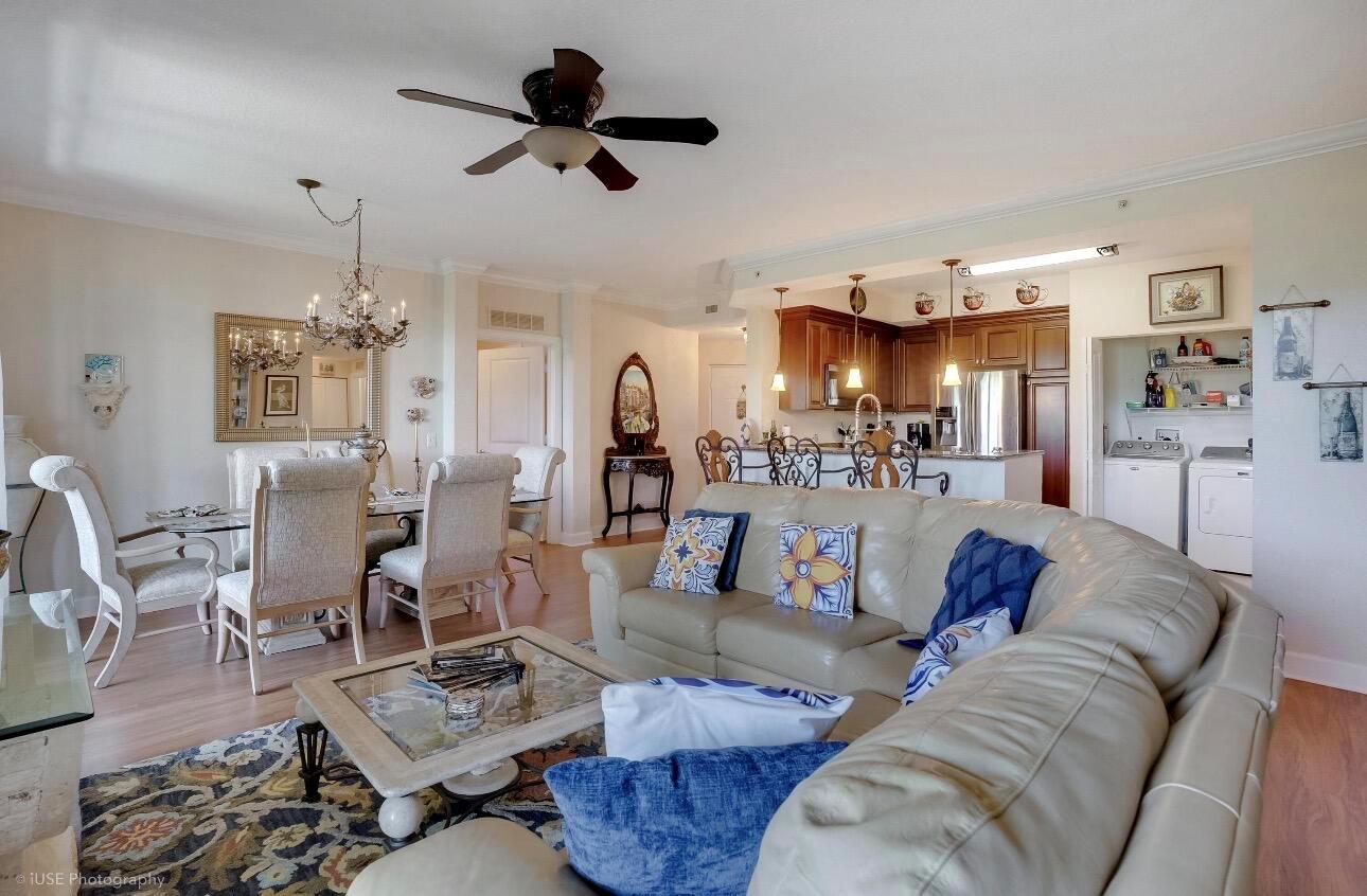 An open-concept living and dining area with a leather sectional, chandelier, and kitchen island — 1690 Renaissance Commons Boulevard # 1404, Boynton Beach FL 33426, BOYNTON BEACH, FL