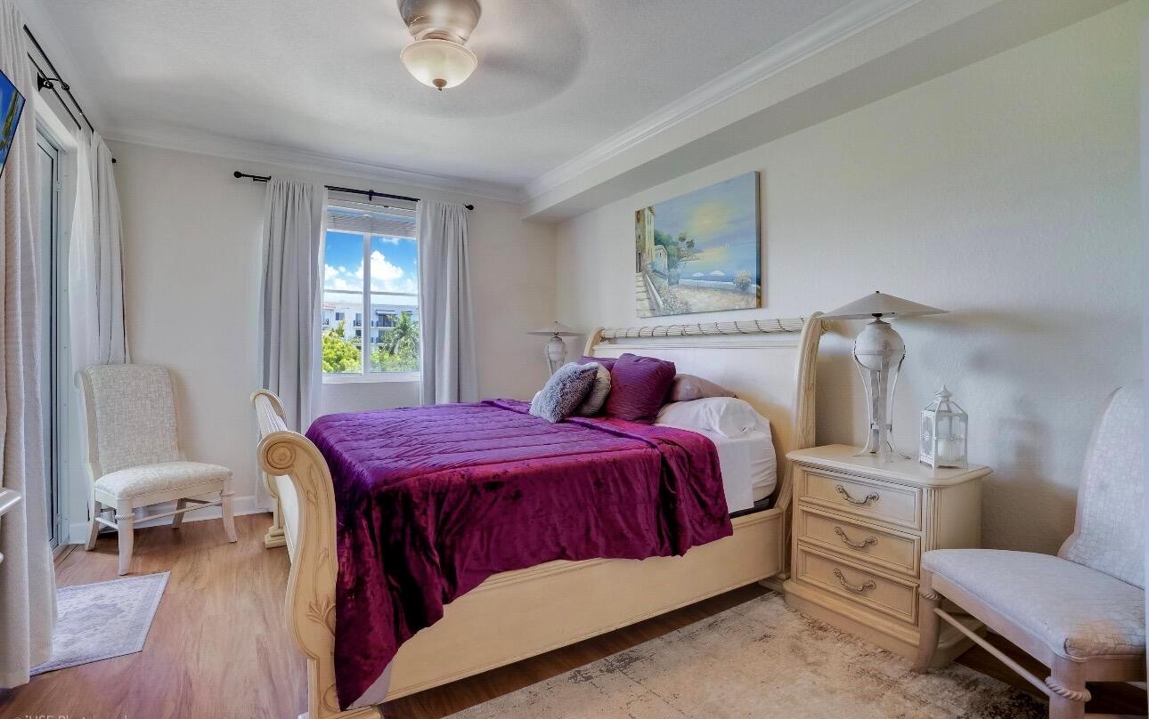 A bedroom features a purple bedspread, a cream-colored sleigh bed, and two matching side chairs — 1690 Renaissance Commons Boulevard # 1404, Boynton Beach FL 33426, BOYNTON BEACH, FL
