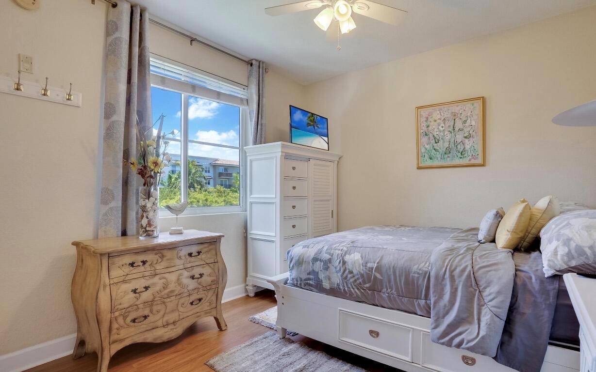 A bedroom features a white bed, a wooden dresser, a tall white cabinet, and a window — 1690 Renaissance Commons Boulevard # 1404, Boynton Beach FL 33426, BOYNTON BEACH, FL