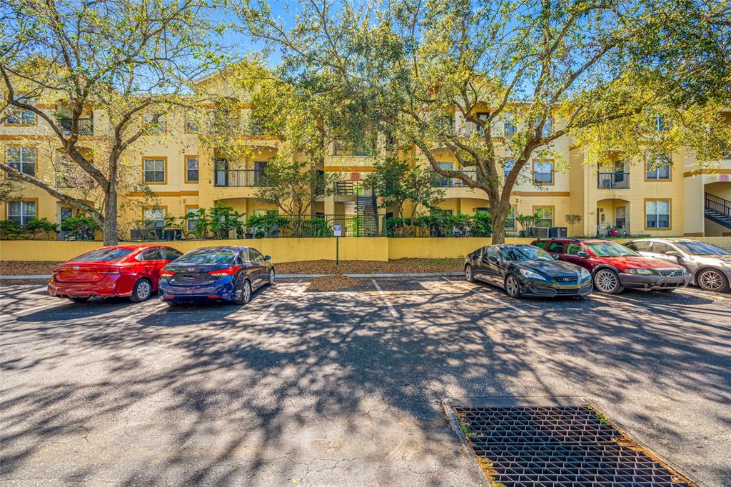 A multi-story apartment building stands behind a parking lot with several parked cars — 5612 PINNACLE HEIGHTS CIRCLE UNIT 206, TAMPA, FL