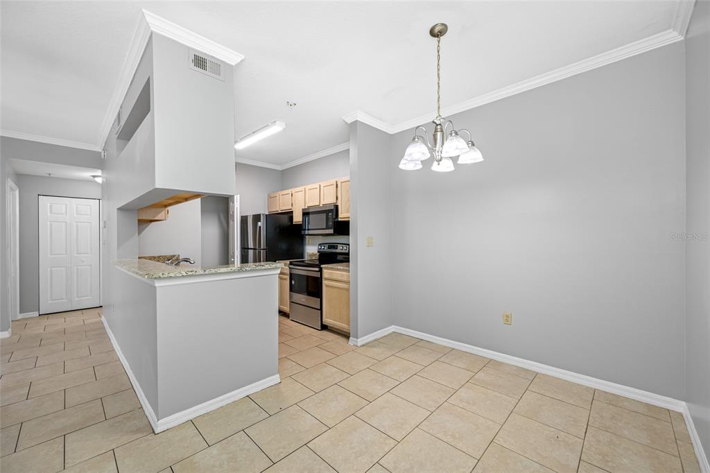 A dining area with tile floors and a chandelier opens to a kitchen with cabinets — 5612 PINNACLE HEIGHTS CIRCLE UNIT 206, TAMPA, FL