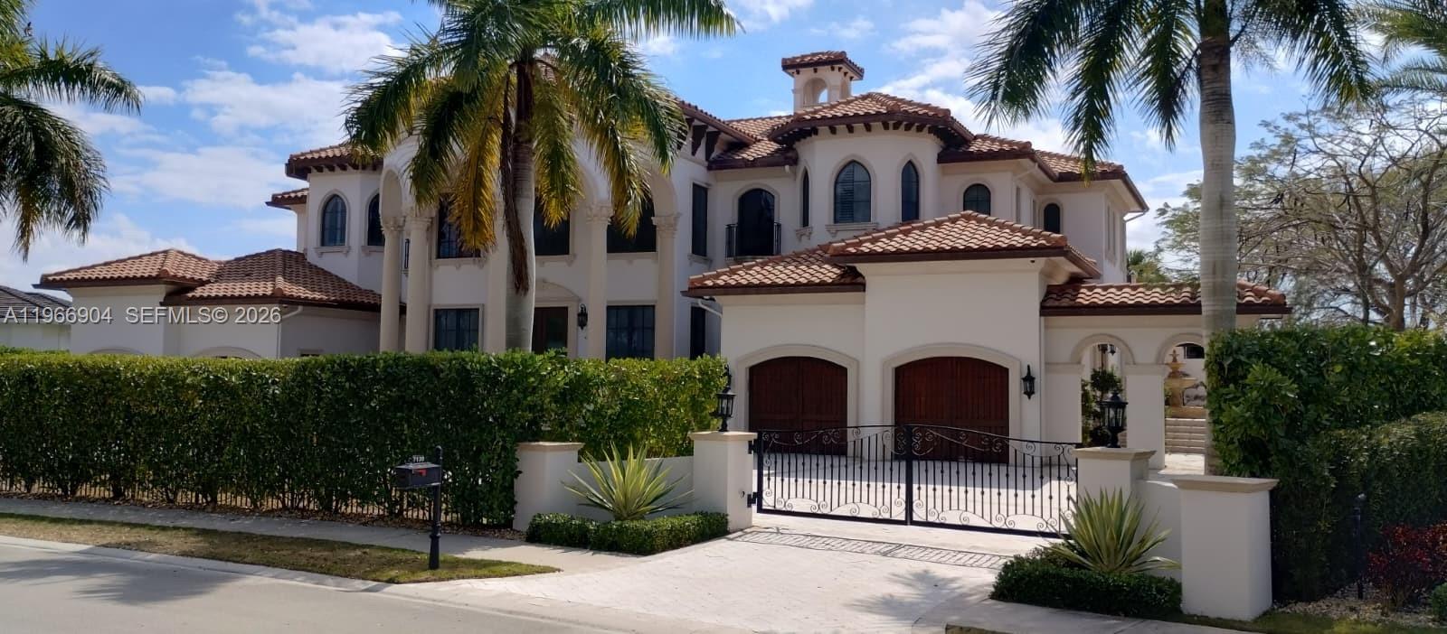A large Mediterranean-style house with a tile roof, arched windows, and a gated driveway — 7130 Lemon Grass Dr, Parkland FL 33076, PARKLAND, FL