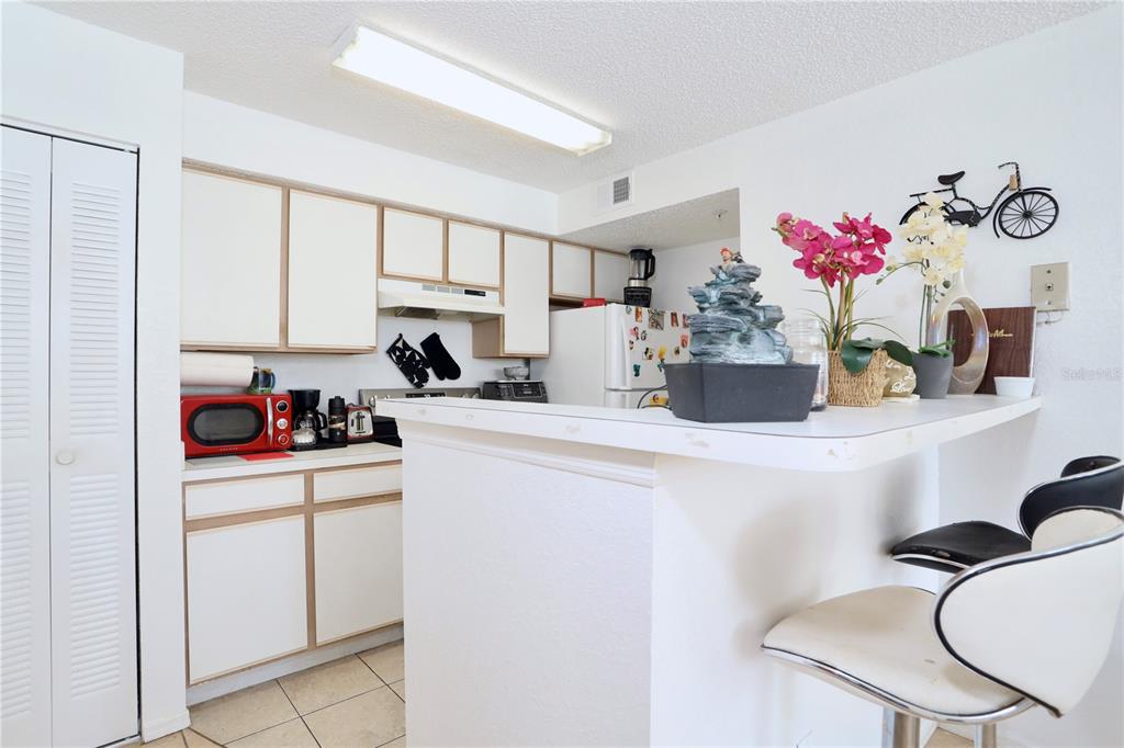 A kitchen features white cabinets, a breakfast bar, and a red microwave — 2209 ANTIGUA PLACE UNIT 828, KISSIMMEE, FL