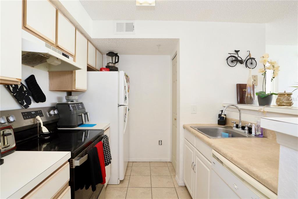 A kitchen features white cabinets, a black stove, a white refrigerator, and a tile floor — 2209 ANTIGUA PLACE UNIT 828, KISSIMMEE, FL