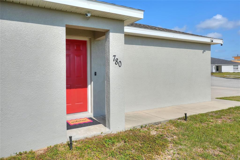 The exterior of a house features a bright red front door and the number 780 — 780 OVERLOOK GROVE DRIVE, WINTER HAVEN, FL