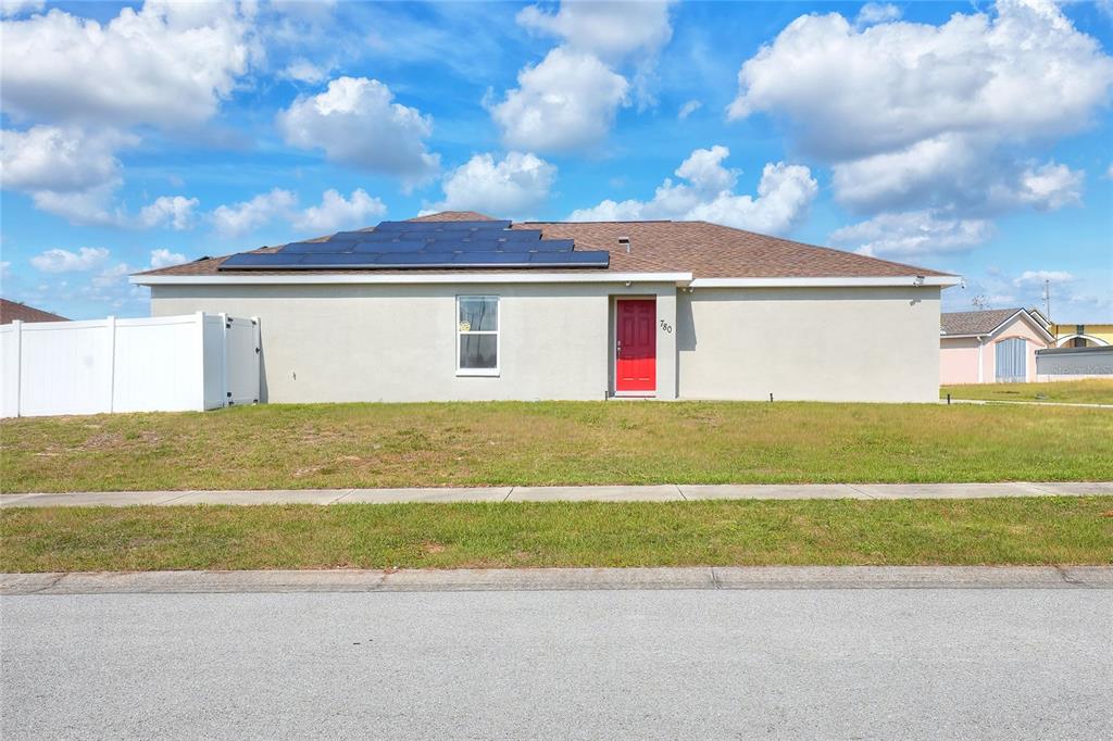 A single-story house with a red front door and solar panels on the roof — 780 OVERLOOK GROVE DRIVE, WINTER HAVEN, FL