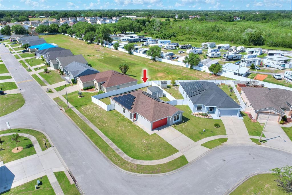 An aerial view shows a suburban neighborhood with houses, solar panels, and a storage shed — 780 OVERLOOK GROVE DRIVE, WINTER HAVEN, FL