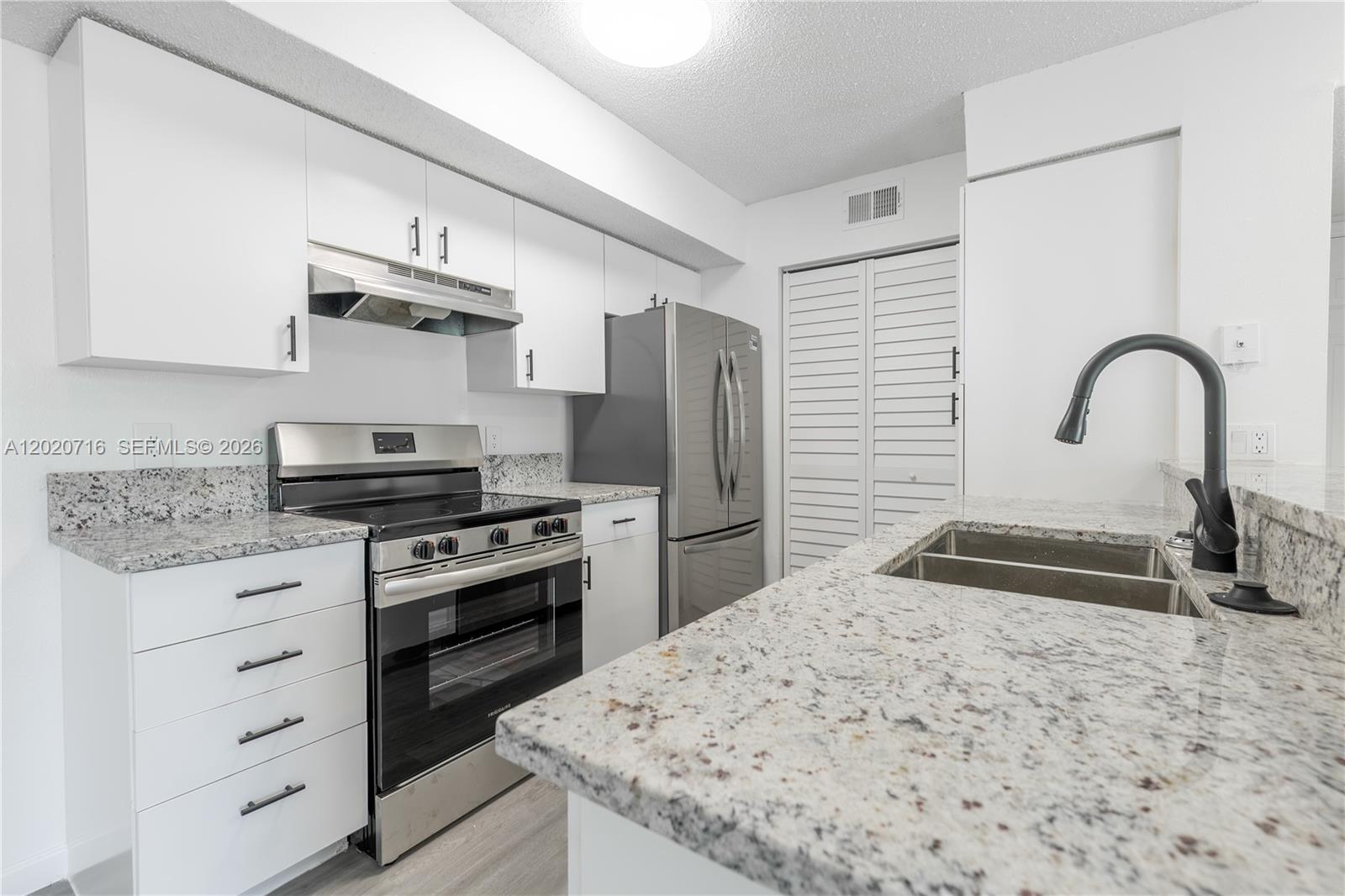A kitchen features white cabinets, granite countertops, stainless steel appliances, and a black faucet — 2094 Arbour Walk Cir # 3018, Naples FL 34109, NAPLES, FL
