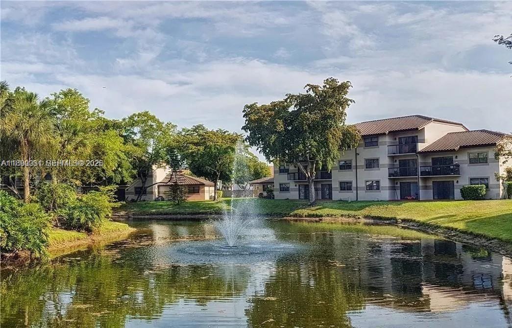 A multi-story apartment building sits behind a pond with a central water fountain — 9937 Nob Hill Pl # 1637, Sunrise FL 33351, SUNRISE, FL