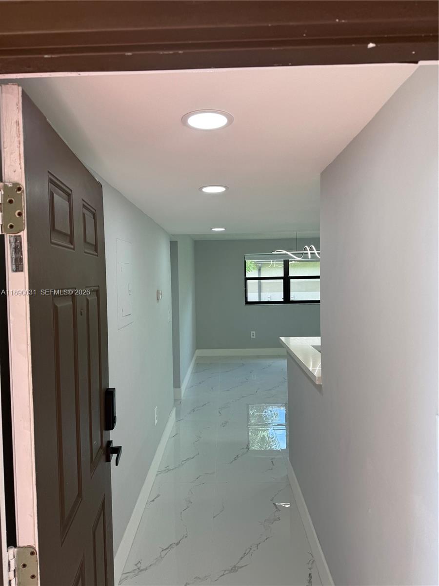 A view from an open doorway into a hallway with white tile flooring and recessed lighting — 9937 Nob Hill Pl # 1637, Sunrise FL 33351, SUNRISE, FL
