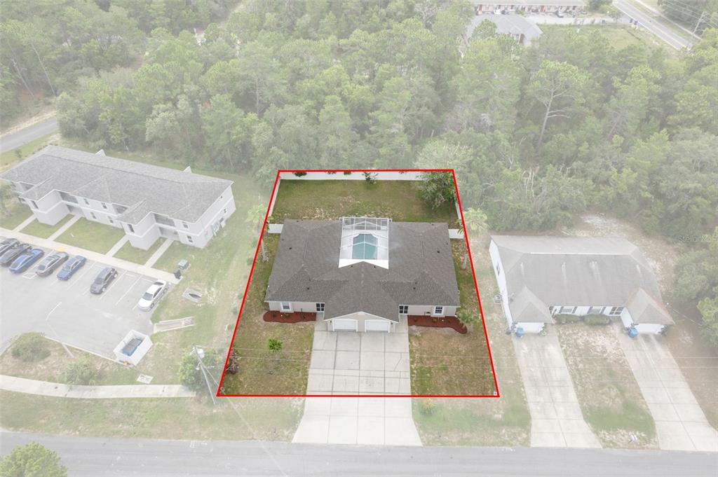 An aerial view shows a duplex with a screened pool and a red-outlined property boundary — 10370 SANDLOR STREET, SPRING HILL, FL