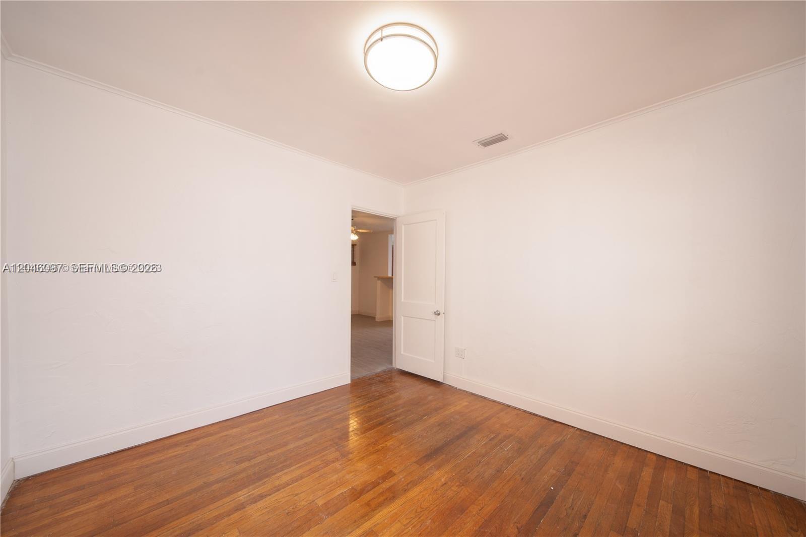 An empty room features white walls, hardwood flooring, and a central ceiling light fixture — 435 SW 33rd Ave, Miami FL 33135, MIAMI, FL