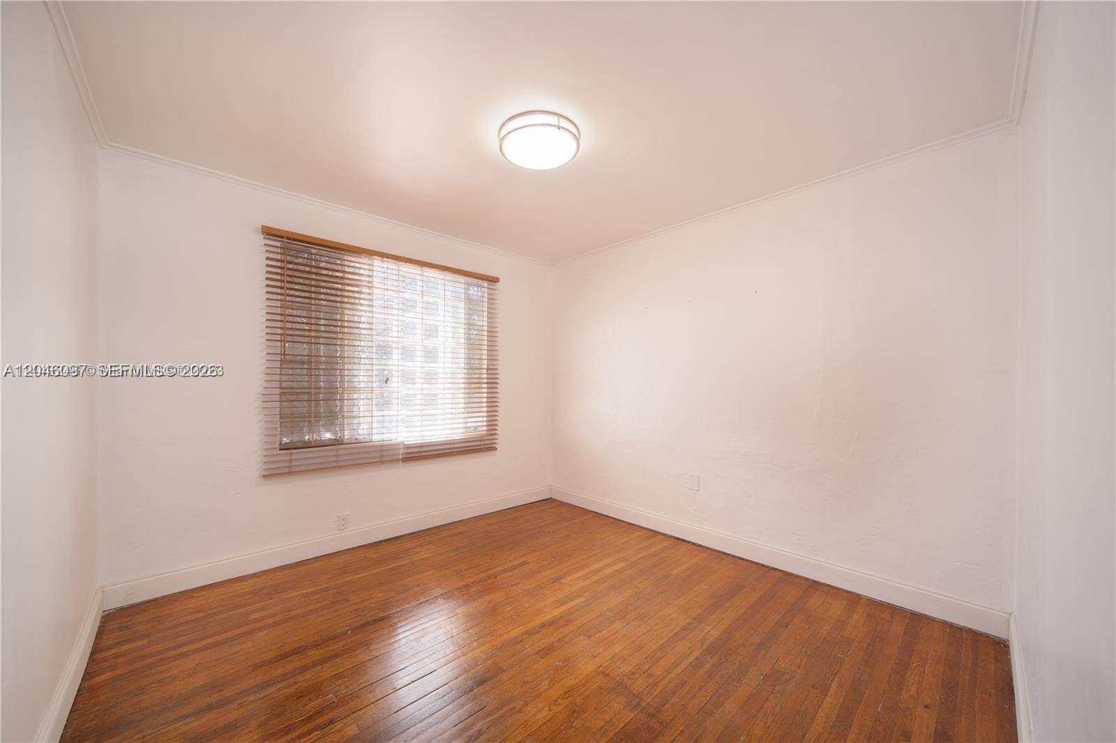 An empty bedroom features white walls, a window with blinds, and hardwood flooring — 435 SW 33rd Ave, Miami FL 33135, MIAMI, FL