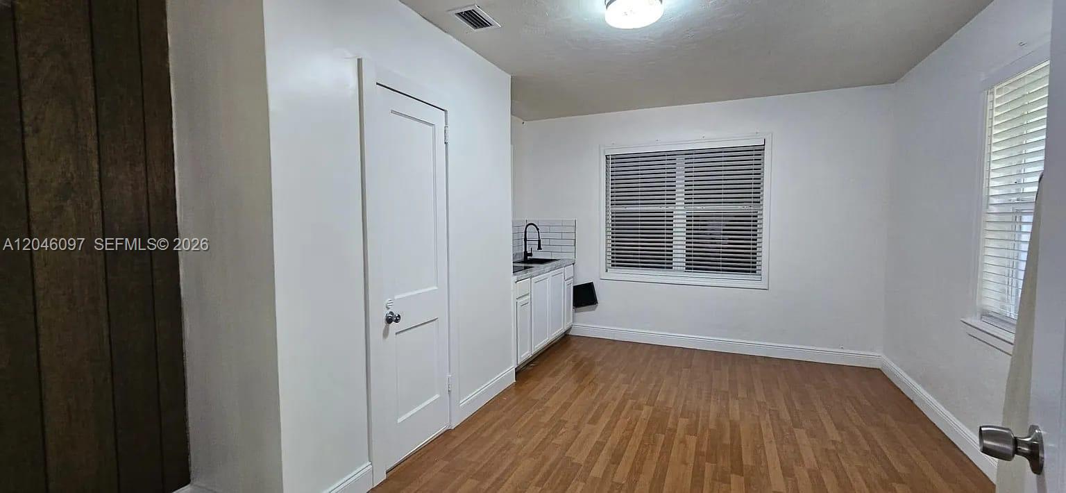 A small kitchen area features white cabinets, a sink, and wood-look flooring — 435 SW 33rd Ave, Miami FL 33135, MIAMI, FL